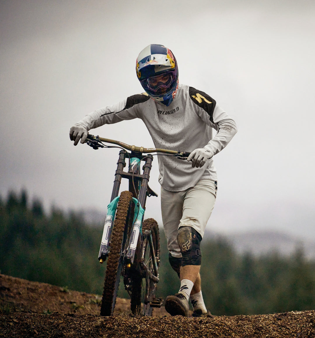 mountain biker walking bike up a hill in riding gear